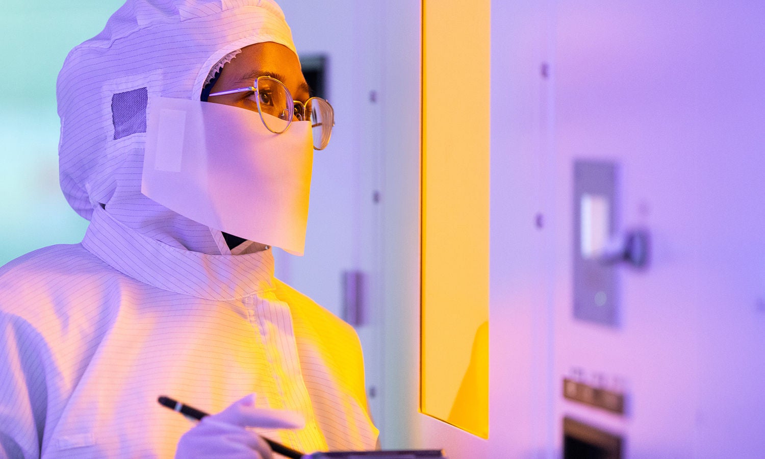 Woman in cleanroom gear holding a clipboard 
